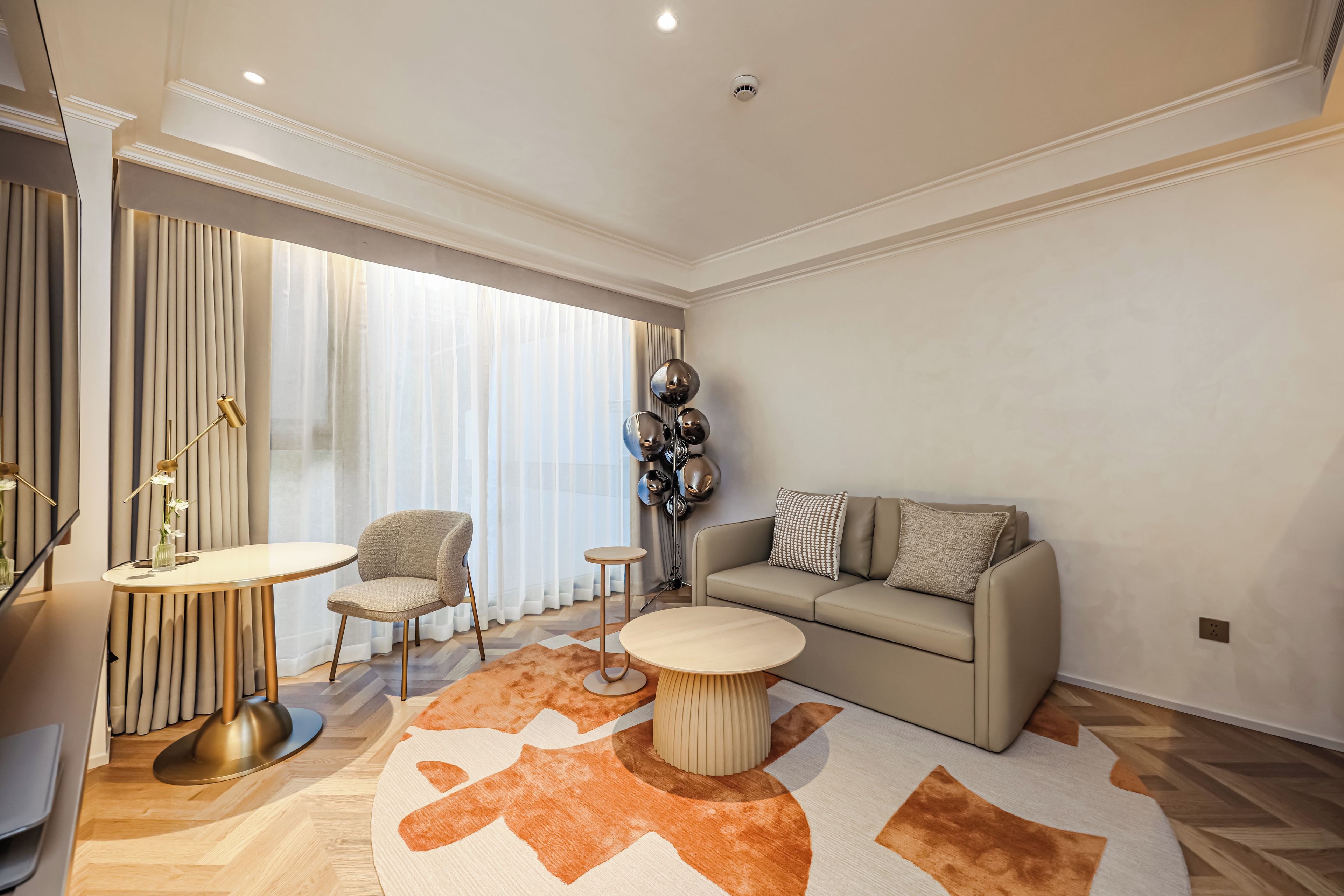 A modern living room with a sofa, a round coffee table, a chair, and a small side table.