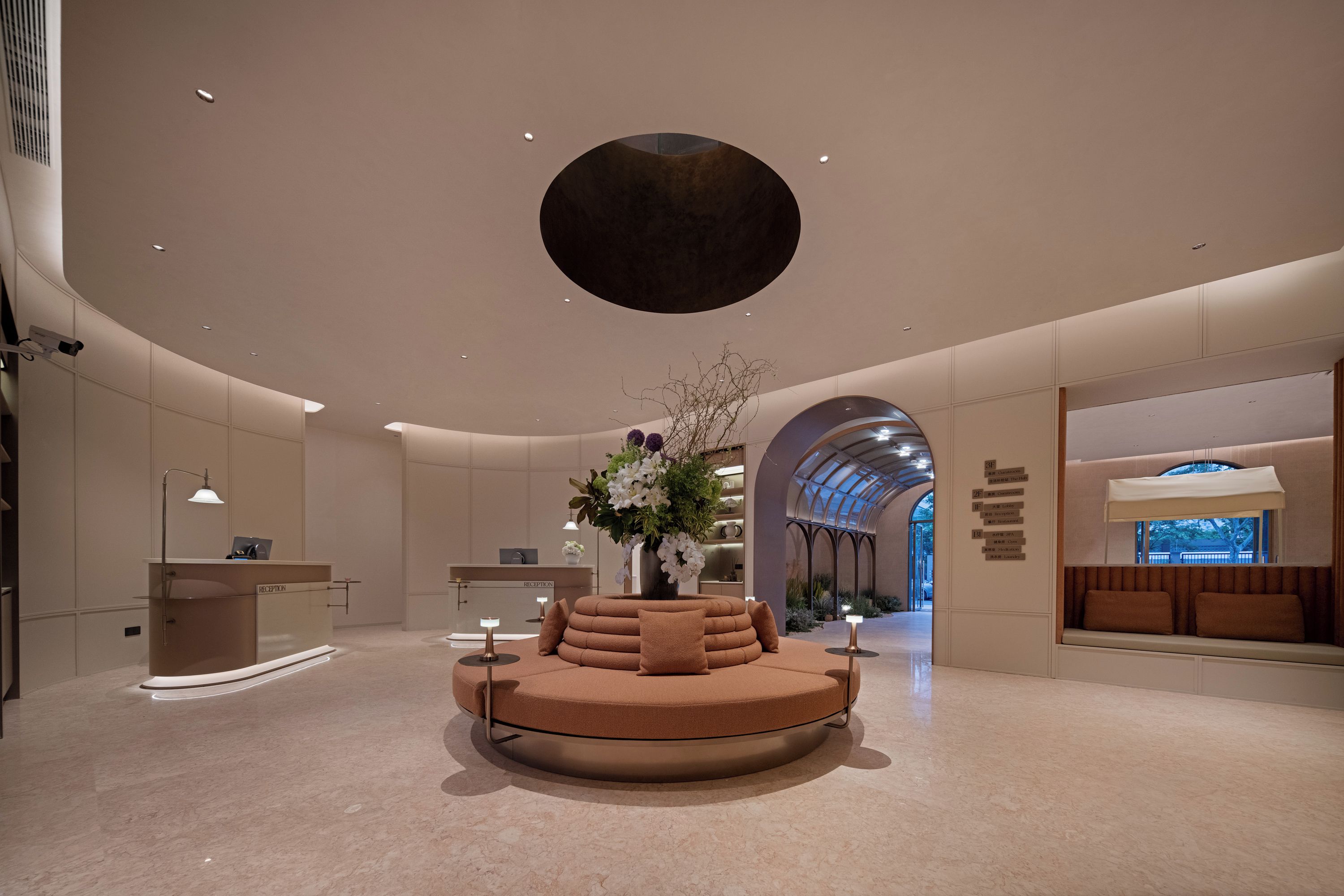 Un vestíbul modern amb una recepció, una zona d'estar circular i un gran lucernari.