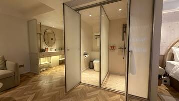 A modern bedroom with a large bed, a bedside table, and a wardrobe with a mirror.