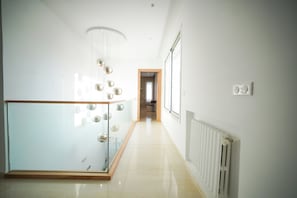 A modern hallway with a glass railing, a ceiling light fixture, and a radiator. - Villa Apollon: Seaside and Luxurious (La Marsa)