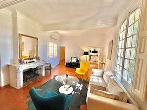 Ein geräumiges Wohnzimmer mit Kamin, Fernseher und einer Couch.