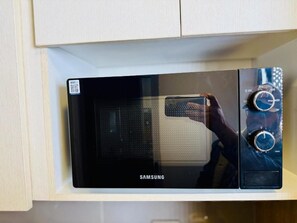 Un microondas Samsung con pantalla digital y perillas de control, ubicado dentro de un mueble de cocina.
