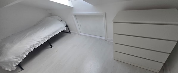 A bedroom with a bed, a dresser, and a door.