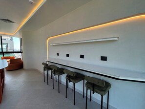 A modern interior with a bar area featuring a long counter and multiple stools. - Ocean-View Pool Just Steps from the Malecón | Apartment for 6 in Miraflores (Miraflores)