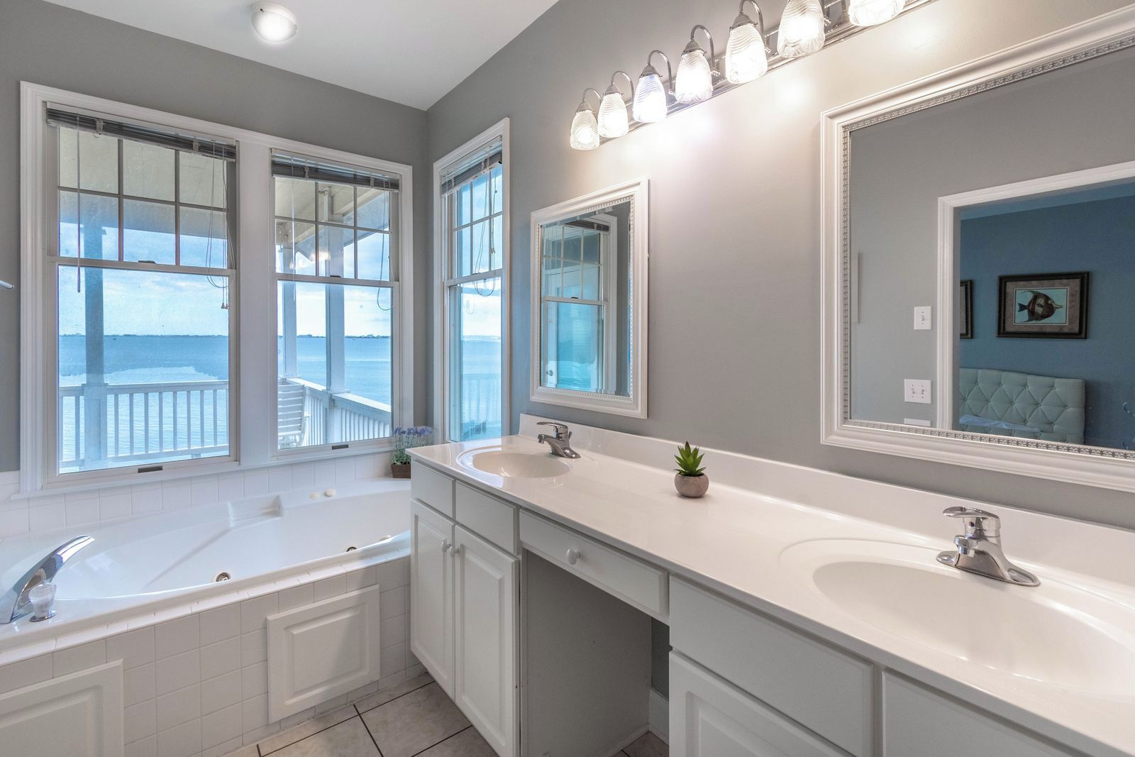 A modern bathroom with a large bathtub, two sinks, and a large mirror.