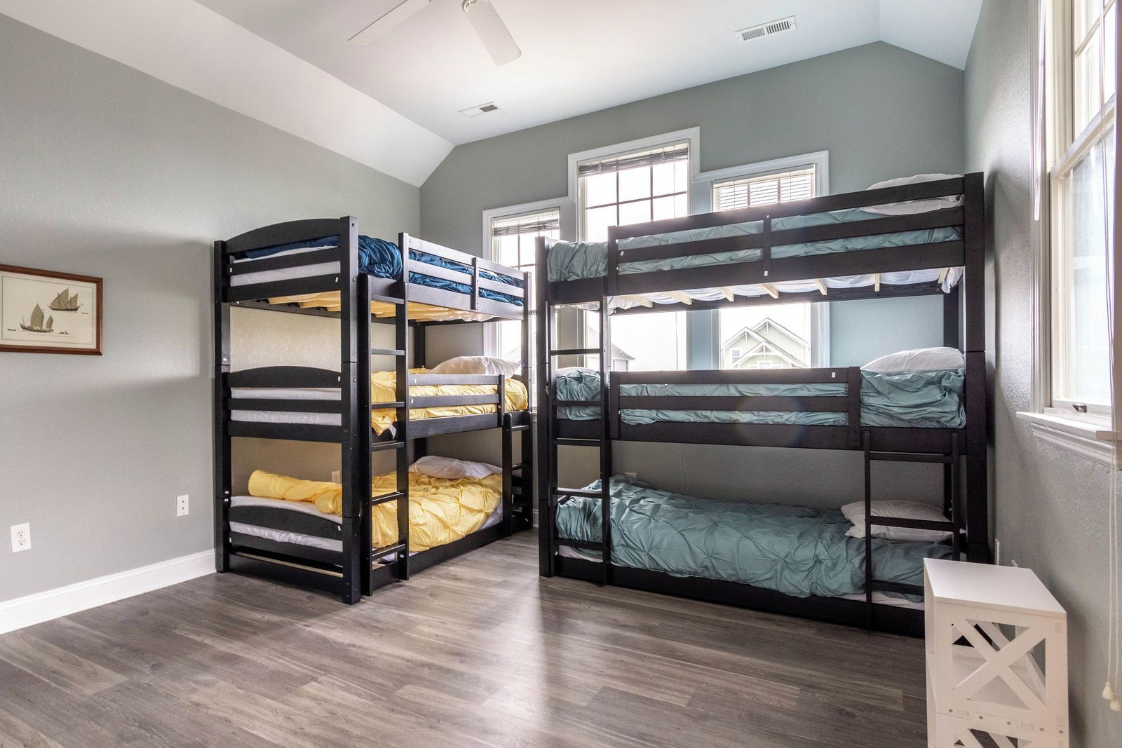 A room with two bunk beds, a framed picture on the wall, and a window with blinds.