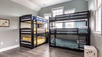 A room with two bunk beds, a framed picture on the wall, and a window with blinds.