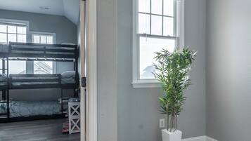 A room with a bunk bed, a potted plant, and a large window.
