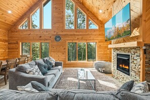A spacious living room with a fireplace, large windows, and a cozy seating area. - New Pet Friendly Home w HotTub, FirePit, PoolTable (McHenry)