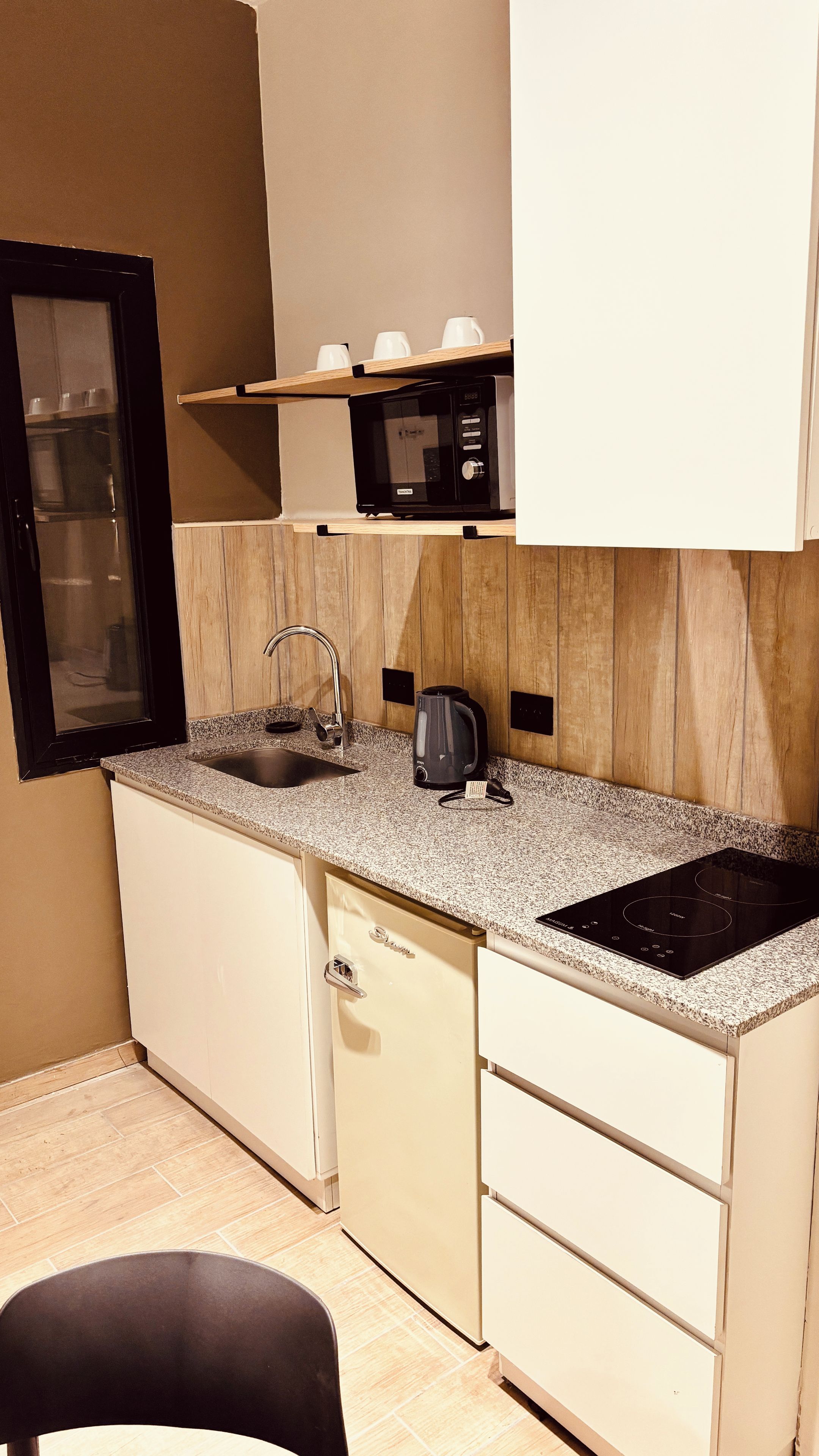 Una cocina compacta equipada con microondas, hervidor y placa de inducción integrada.