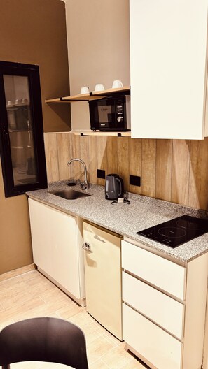 A compact kitchen with a microwave, kettle, and a built-in induction cooktop.