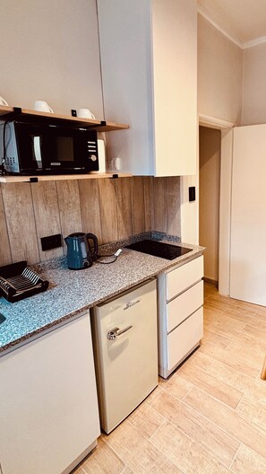 A compact kitchen with a microwave, kettle, and a small countertop.