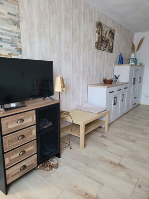 A modern living room with a TV, wooden cabinet, and a small table.