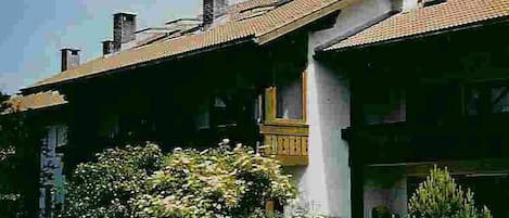 A traditional building with a sloped roof, a visible chimney, and a small balcony.