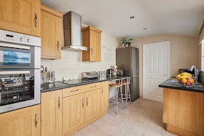 A modern kitchen with wooden cabinets, stainless steel appliances, and a bar area with stools. - Host & Stay | Norwood Street (Scarborough)