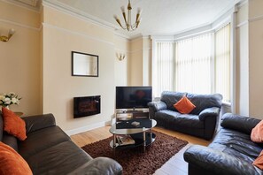 A living room with two sofas, a coffee table, a flat-screen TV, and a chandelier. - Host & Stay | Norwood Street (Scarborough)