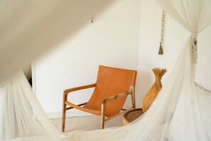 Ein Zimmer mit einem Holzstuhl, einer weißen Wand und einem hängenden Dekorationsobjekt.