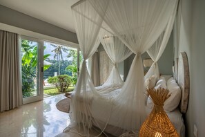 Ein Schlafzimmer mit Himmelsbett, großen Fenstern und Blick auf Grün.