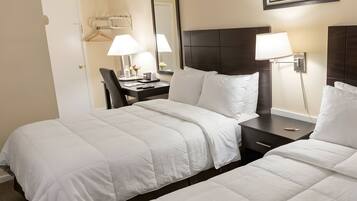 Een hotelkamer met twee bedden, een bureau, een stoel, een lamp en een lijst aan de muur.
