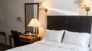 A hotel room with a large bed, a bedside table with a lamp, and a chair. - North Star Motel (Shelburne)