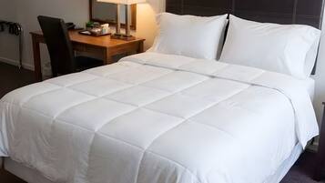 Een hotelkamer met een groot bed, een nachtkastje met een lamp en een stoel.