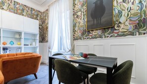 Ein Essbereich mit einem schwarzen Tisch, grünen Stühlen und einem weißen Schrank mit Regalen.