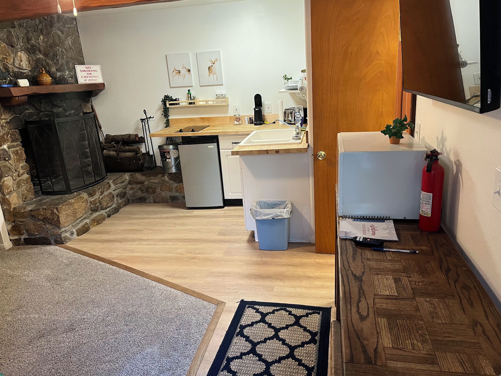A compact kitchen with a stone fireplace, a sink, and a refrigerator.