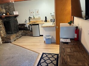 A compact kitchen with a stone fireplace, a sink, and a refrigerator. - guhos ranch (Big Bear Lake)