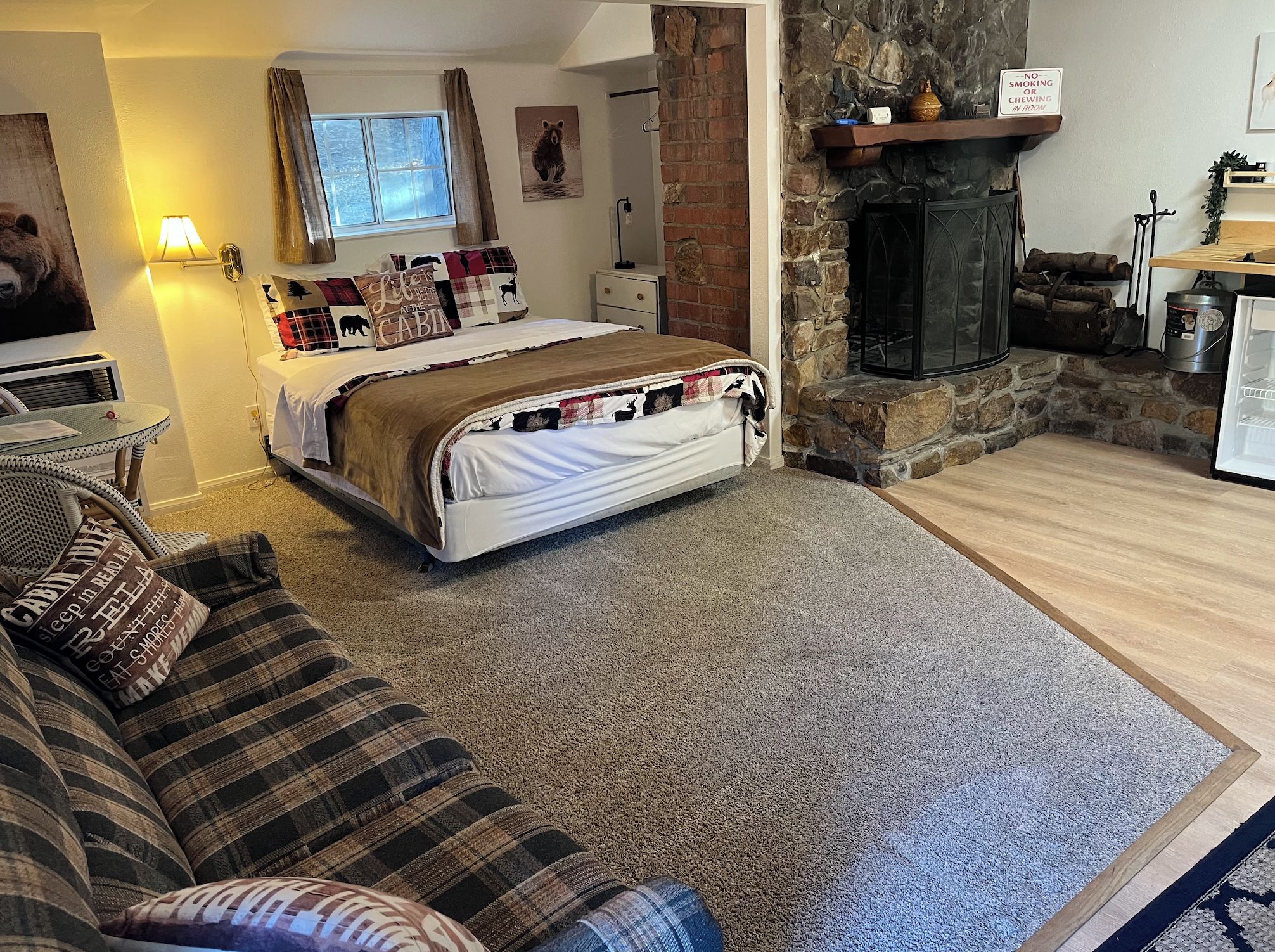 Una habitación acogedora de estilo cabaña con cama, chimenea, mesa de comedor y sofá.