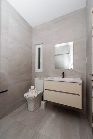 Een moderne badkamer met toilet, bidet en wastafel.