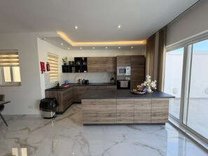 Cozinha moderna com ilha central, eletrodomésticos embutidos e uma grande janela que proporciona iluminação natural.