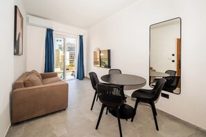 Ein modernes Wohnzimmer mit einer Couch, einem Esstisch, Stühlen und einem großen Spiegel.