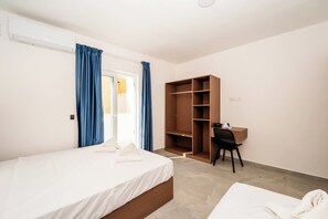 A bedroom with a bed, a desk, and a wardrobe. - New Central 1 Bed Apartment in Qawra (St. Paul's Bay)