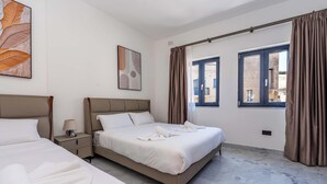 Une chambre d’hôtel avec deux lits, une table de chevet, une lampe et une vue sur l’extérieur par une fenêtre.