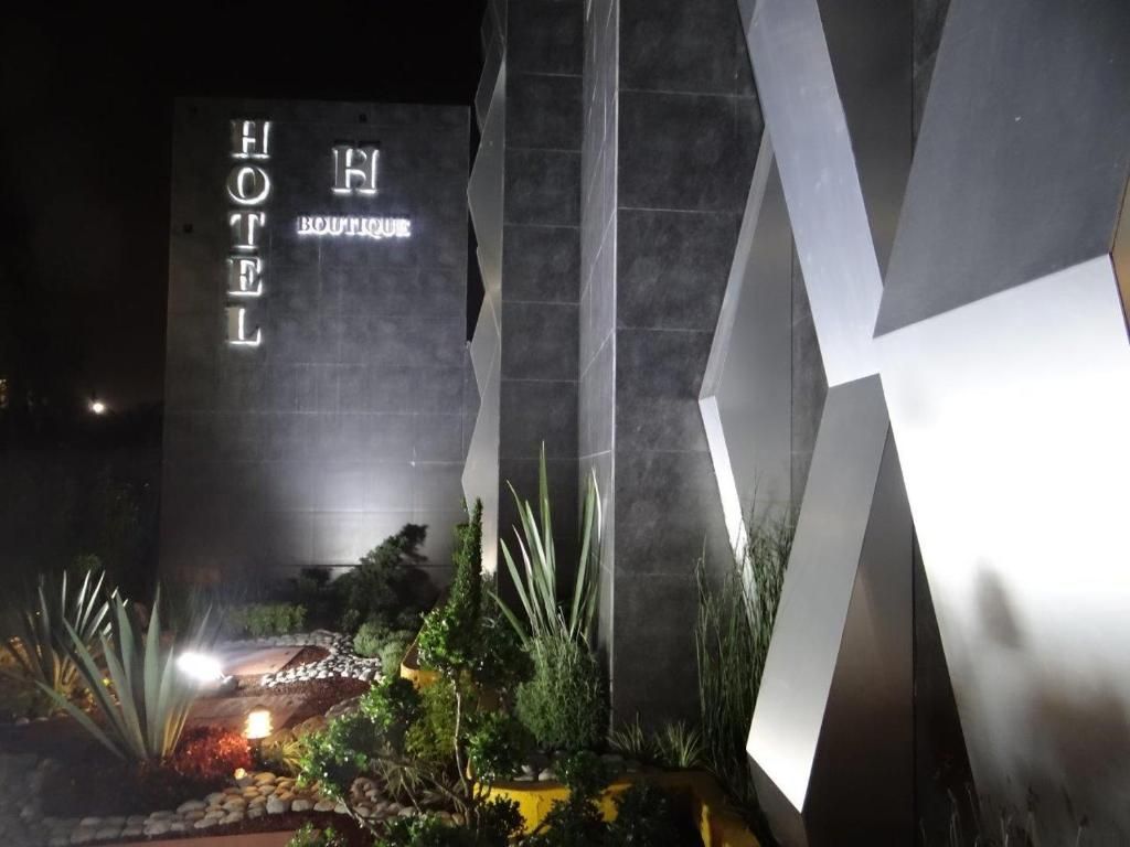 Entrada de hotel com fachada geométrica moderna e placa bem iluminada.