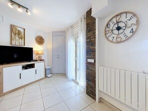 Ein modernes Wohnzimmer mit Flachbildfernseher, einer Uhr und einer Wand mit Steinverkleidung.