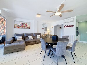 A modern living room with a sectional sofa, a dining table with chairs, a ceiling fan, and a kitchen area labeled 'Cuisine'. - DRASSANES Rosas / Roses – INTERimmo (Rosas / Roses)
