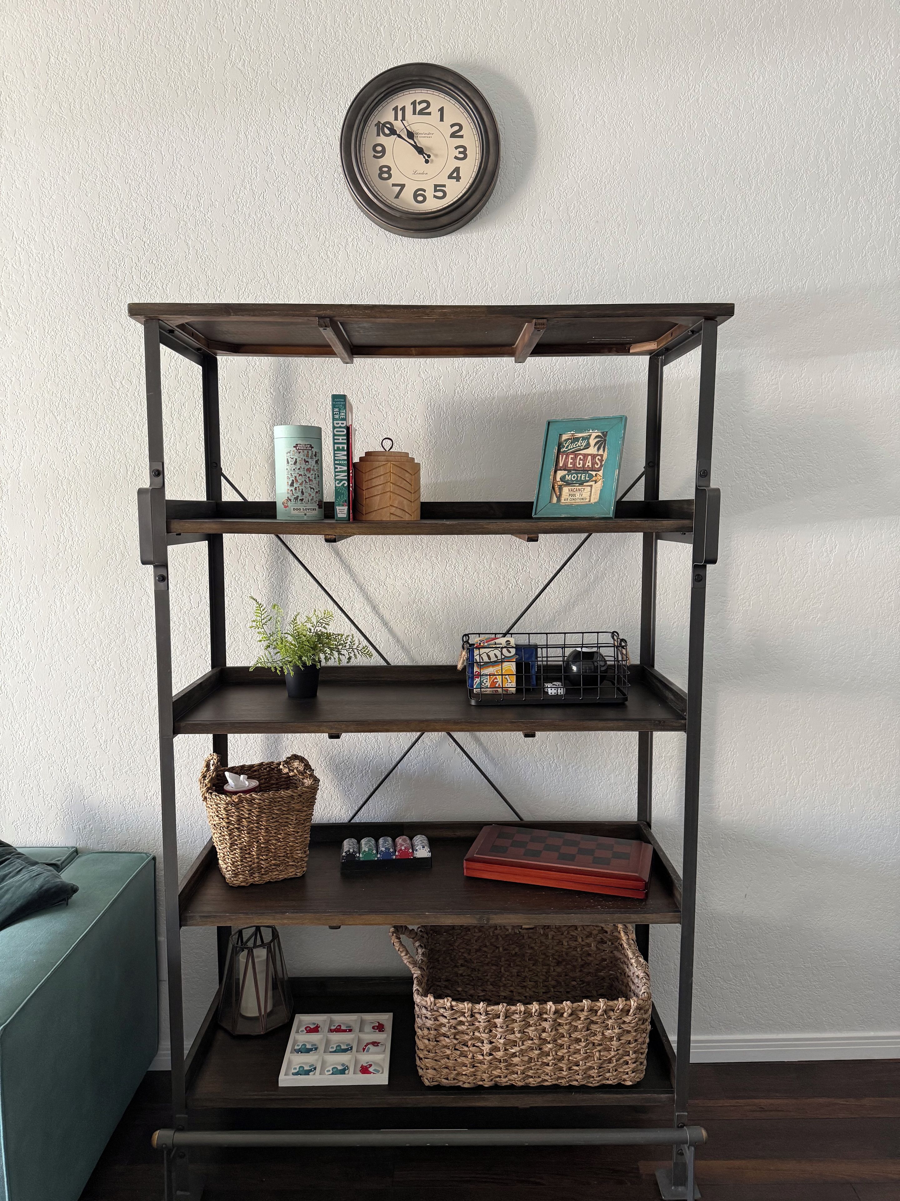 A multi-tiered metal shelf unit with various items on each shelf, including books, a framed picture, and decorative objects.