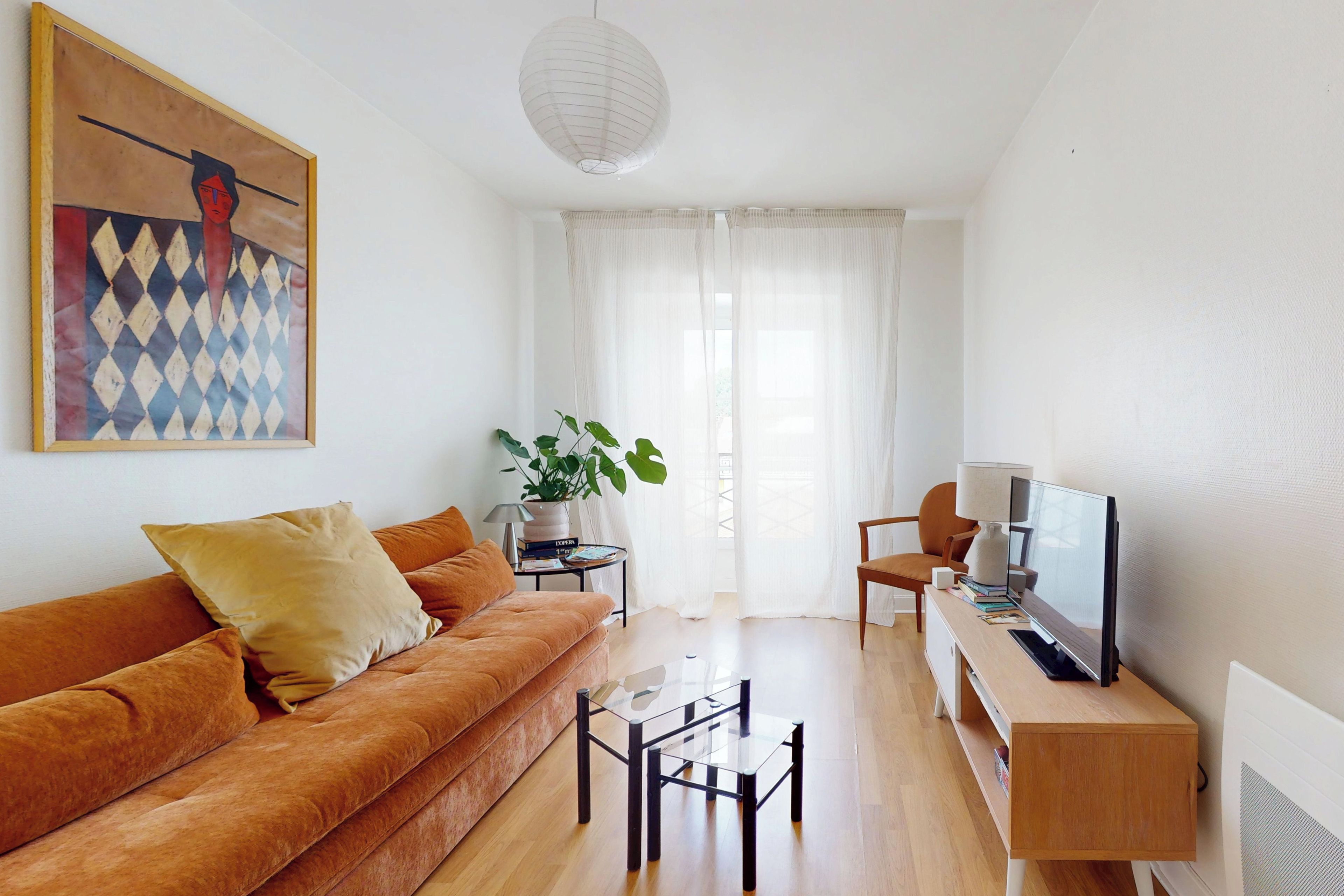 A modern living room with a sofa, coffee table, TV, and a painting on the wall.