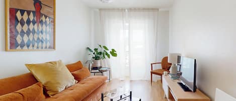 A modern living room with a sofa, coffee table, TV, and a painting on the wall.