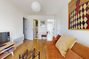 A modern living room with a flat-screen TV, a glass coffee table, and a sofa with cushions. - Cozy 1-bedroom apartment, 10 minutes from downtown—Tram stop 5 minutes away (Nantes)