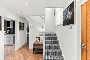 A modern interior with a staircase, a kitchen area, and a dining space. - Ashcombe House • Sleeps 9 • Pool Table • Snug Room • SkyTV • Xbox • Driveway Parking • Yoko Property (Worthing)