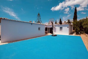A pool area with a basketball hoop, surrounded by white buildings and trees. - Villa Maris - Your Place in the Sun (Carvoeiro)