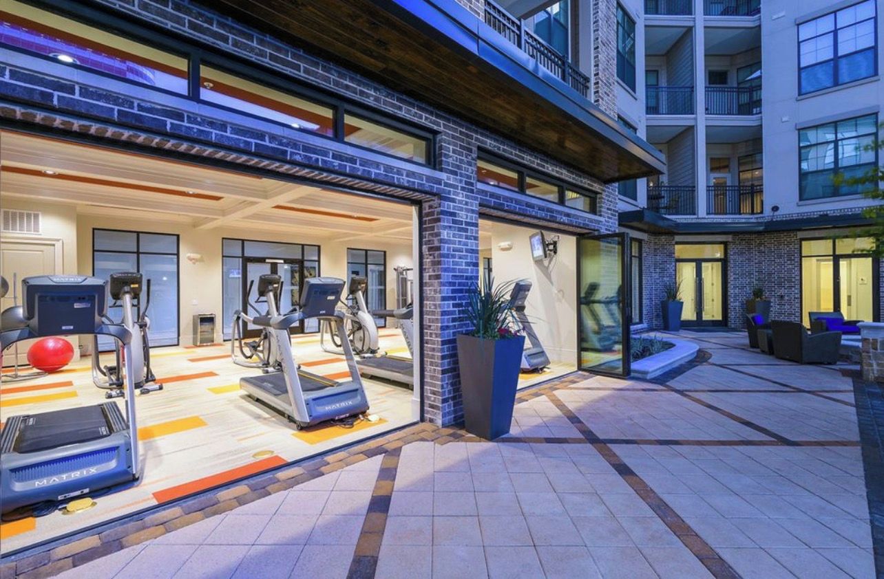 Un immeuble à plusieurs étages qui comprend une salle de sport équipée de tapis de course et de ballons d’exercice.
