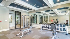 Academia com equipamento de musculação, espelhos e um banco.
