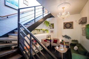 A modern interior with a staircase, a chandelier, and a green sofa.