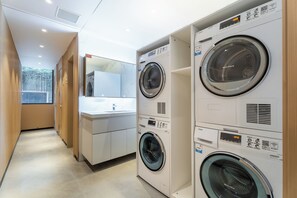 A laundry area with multiple Haier washing machines, a mirror, and a sink.