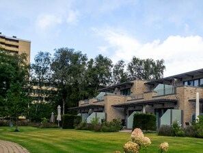 A modern building with a brick facade, large windows, and a well-maintained lawn with flowers. - Holiday Home With 1 Bedroom (St. Peter-Ording)