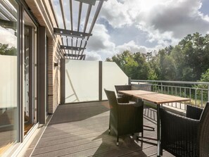 A balcony with a table and chairs, a pergola, and a view of trees. - Holiday Home With 1 Bedroom (St. Peter-Ording)