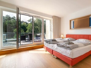 A hotel room with a large sliding glass door leading to an outdoor deck, a bed with red headboard, and a wall-mounted TV. - Holiday Home With 1 Bedroom (St. Peter-Ording)